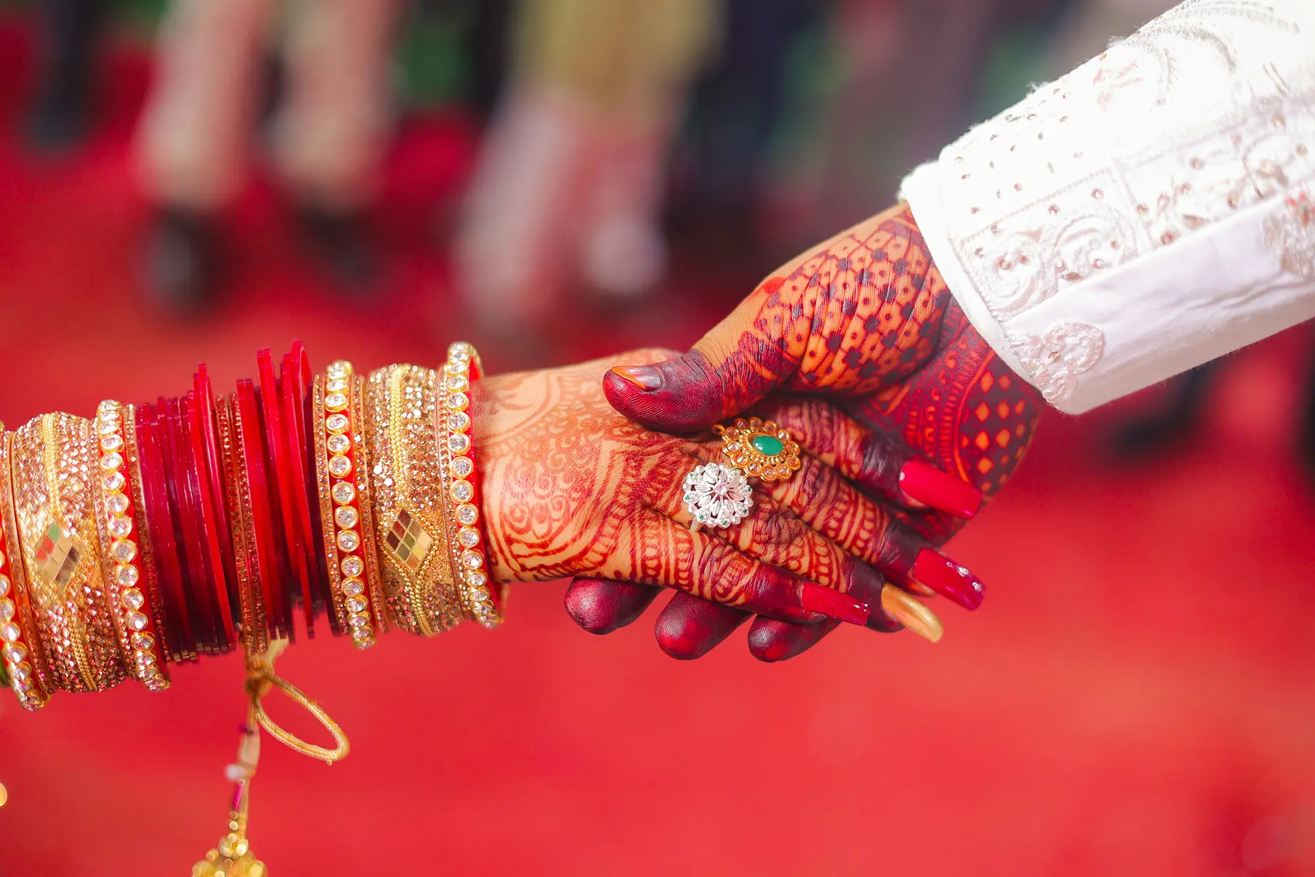 Couple holding hands with red bangles